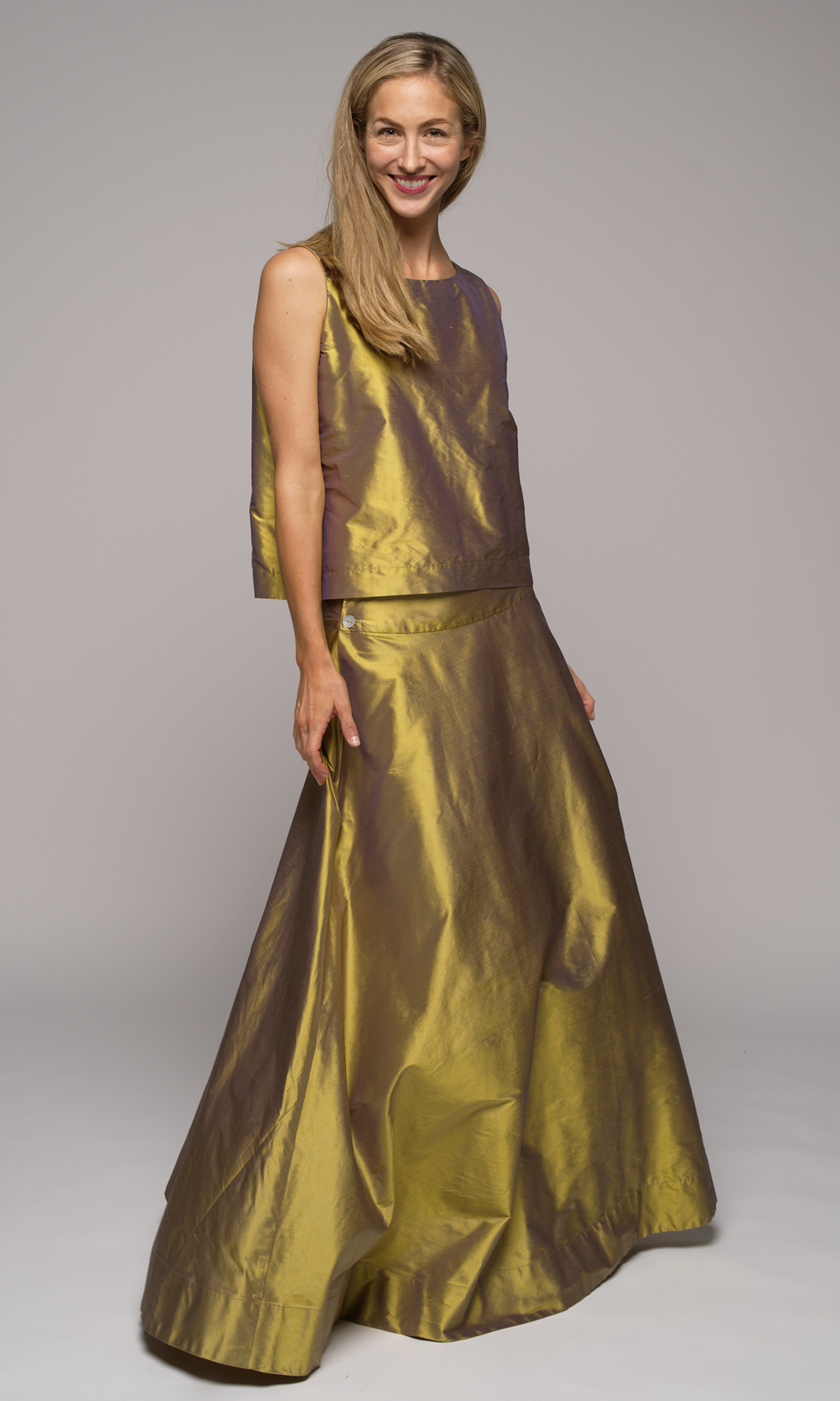 Woman wearing a gold silk sleeveless top with matching gold silk floor length flowing skirt.