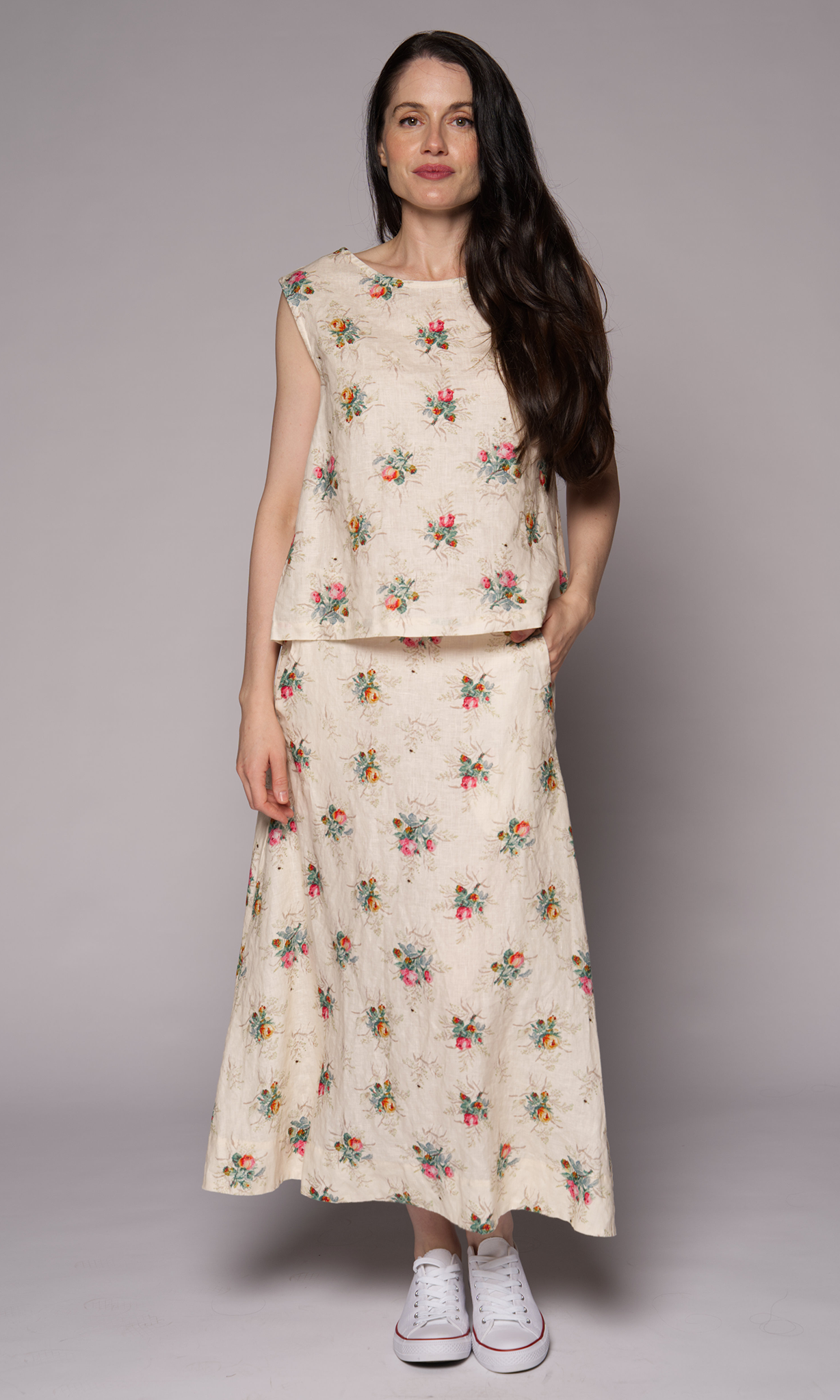 Dark-haired woman in a cream floral singlet top and matching skirt.