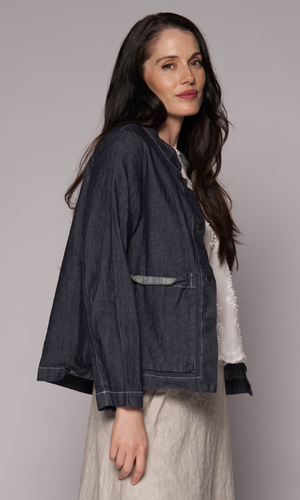Darked haired women wears a denim jacket with a large square pocket on the side.