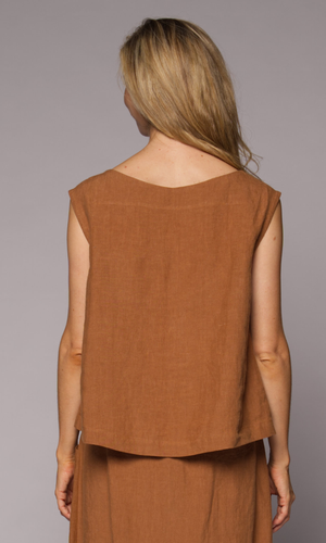 A woman, viewed from behind, wears a sleeveless rust-brown linen top and matching skirt.