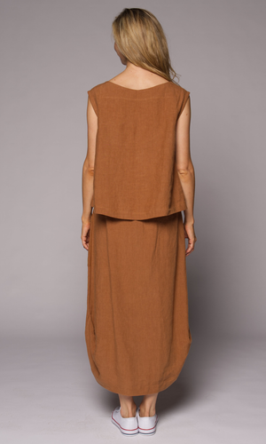 A woman viewed from behind wearing a sleeveless rust-brown linen vest and matching maxi skirt set.