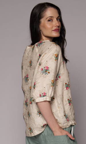 Close-up of the side of a dark-haired woman wearing a floral 3/4-sleeve top and light green pants, showing pocket detail.