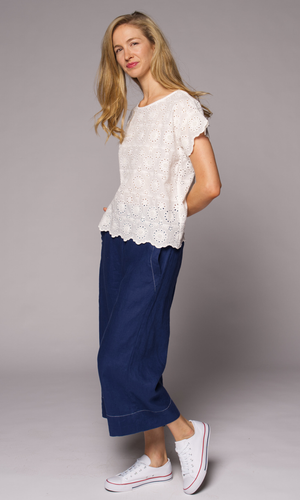 Blonde haired woman modelling a white lace top, with denim pants.