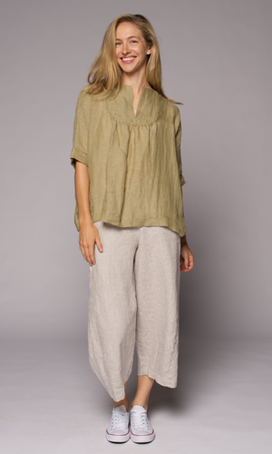 Blonde-haired woman modelling a light green linen top and linen pants.