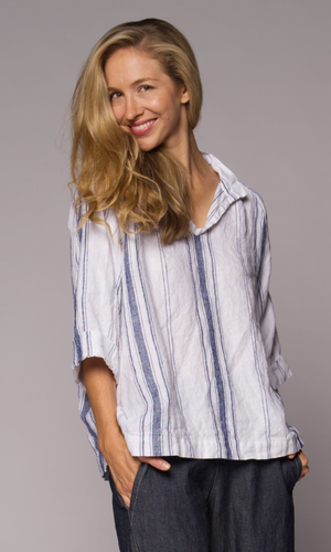 Close-up of a blonde wearing a collared top and denim pants.