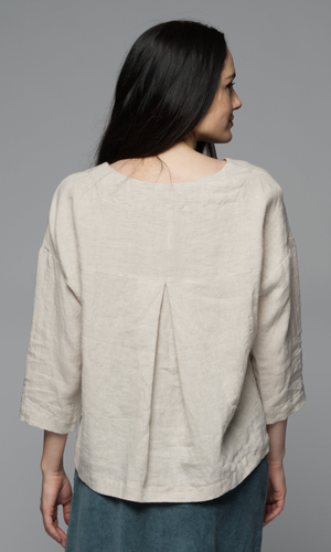 A woman wearing a beige top.