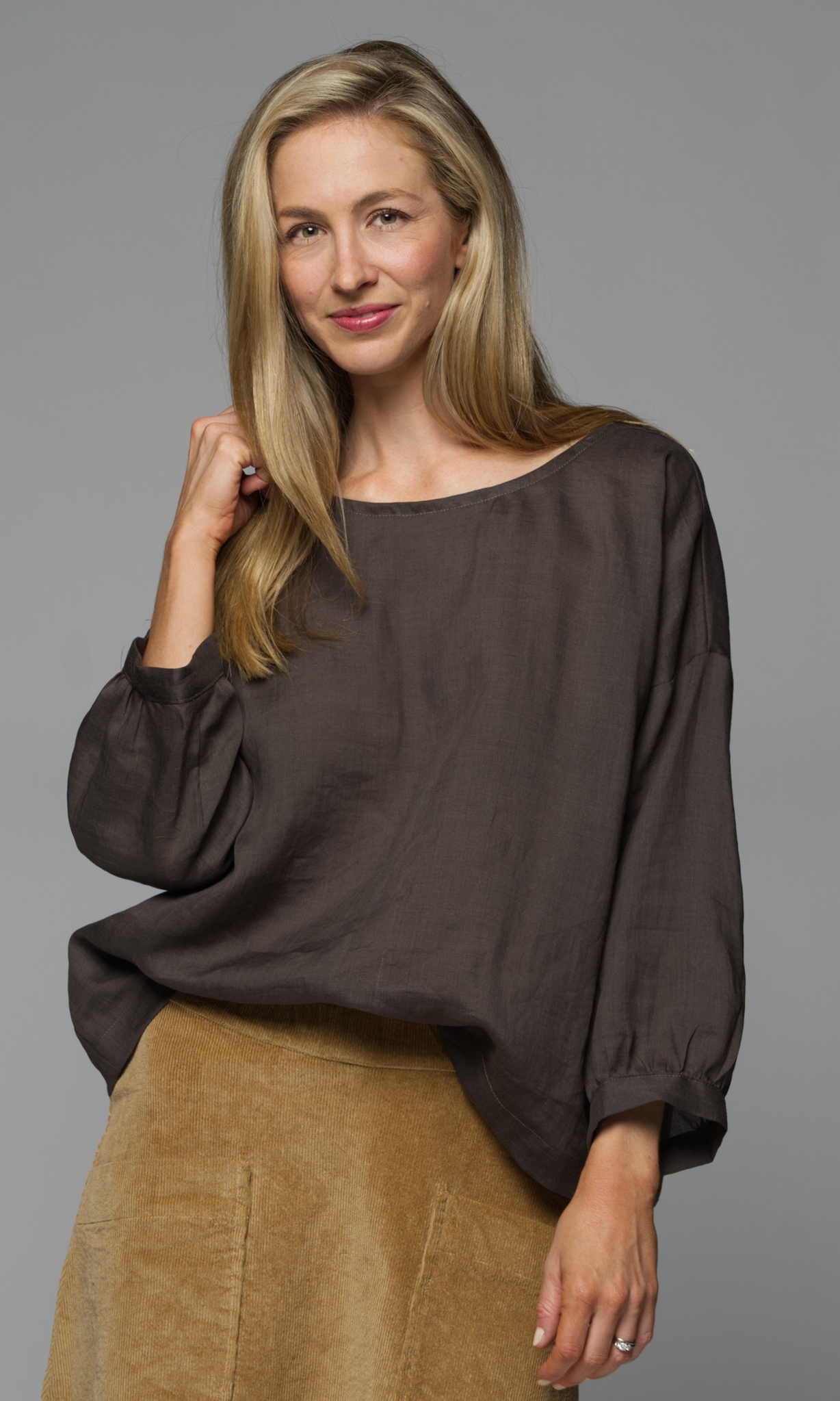 A woman wearing a dark brown blouse and a tan skirt.