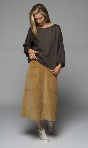 A woman wearing a brown top and a camel coloured skirt.