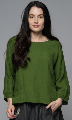 Woman wearing a green blouse and a denim skirt.