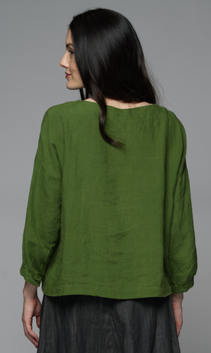 Woman wearing a green blouse and a denim skirt.
