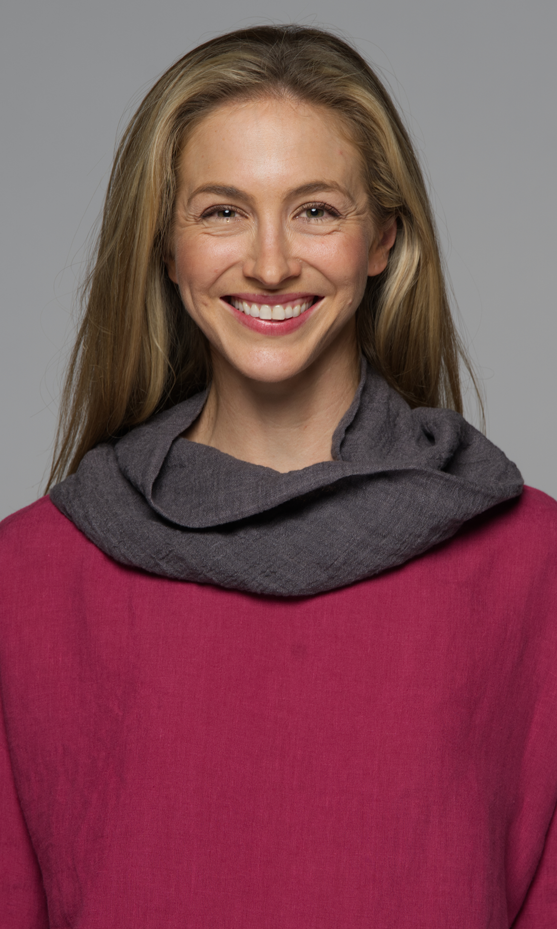 A women wearing a grey scarf on a dark pink top.