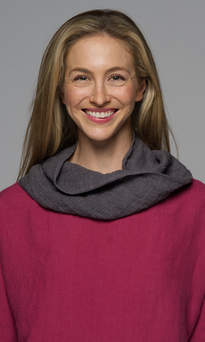 A women wearing a grey scarf on a dark pink top.