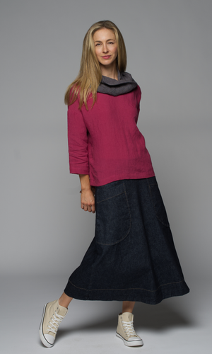 A women wearing a grey scarf on a dark pink top and a denim blue skirt.