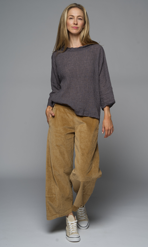 A women wearing a grey top and camel corduroy pants. 