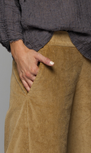Close-up of a person wearing brown corduroy pants and a gray sweater.