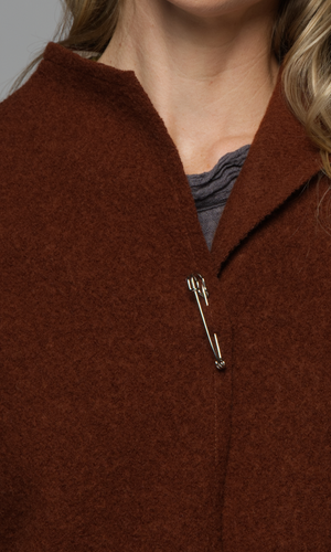A close up of a woman's neckline in a rust coloured jacket with a grey top.