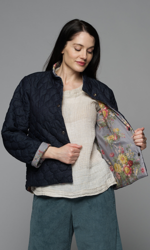 Women with dark brown hair in a denim blue jacket with quilted details, showing reverse side with cotton floral pattern.