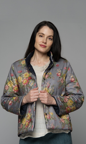 Women with dark brown hair in a denim blue jacket with quilted details, showing reverse side with cotton floral pattern.