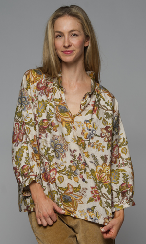 A woman wearing a long sleeve top with a floral pattern and corduroy beige pants.