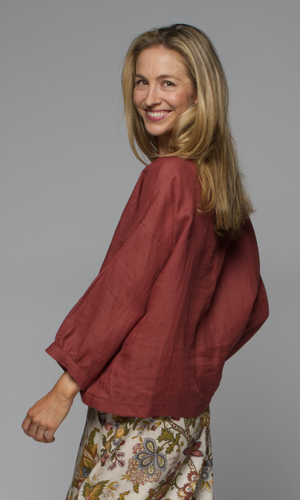 A woman wearing a rust coloured blouse.