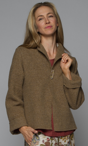A woman wearing a brown v-neck jacket with a red top and floral skirt.