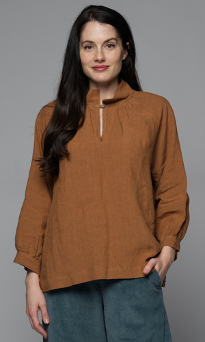 A woman wearing a long-sleeve brown top and mid-blue pants.
