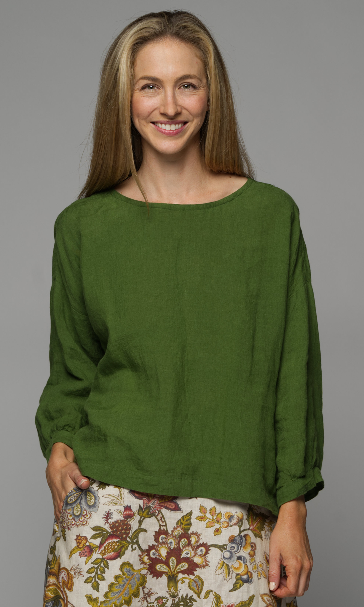 Woman wearing a green blouse with a floral skirt.
