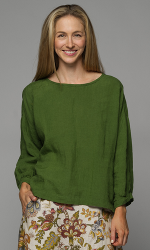 Woman wearing a green blouse with a floral skirt.