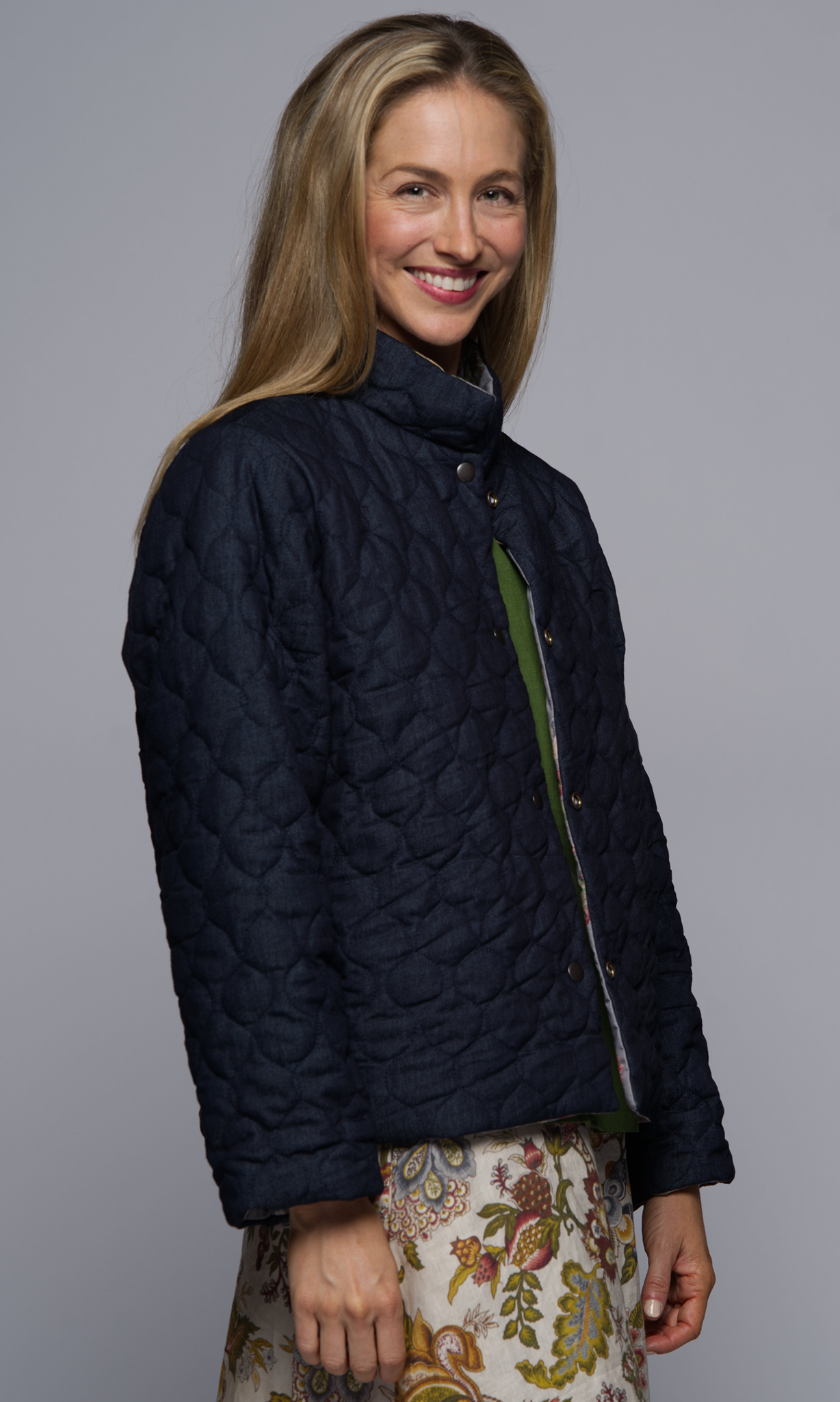 Women with blond hair in a denim blue jacket with quilted details.
