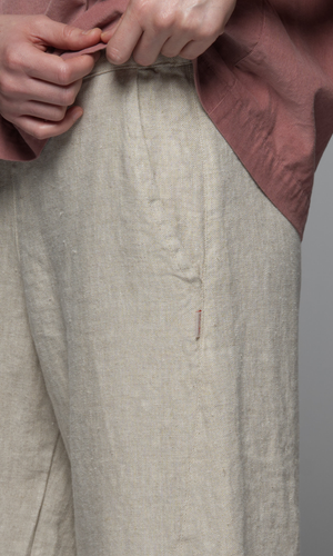 Close-up of beige pants with a pink garment in the background.