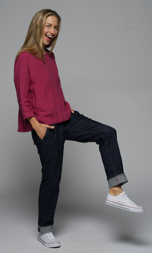 Woman wearing a pink blouse and denim blue jeans, with white sneakers.