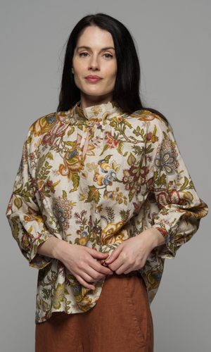 A woman wearing a long sleeve top with a floral pattern and corduroy beige pants.