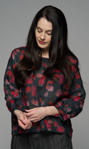 A woman wearing a black sweater with red floral patterns.