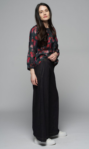 A woman wearing a floral blouse and black pants.