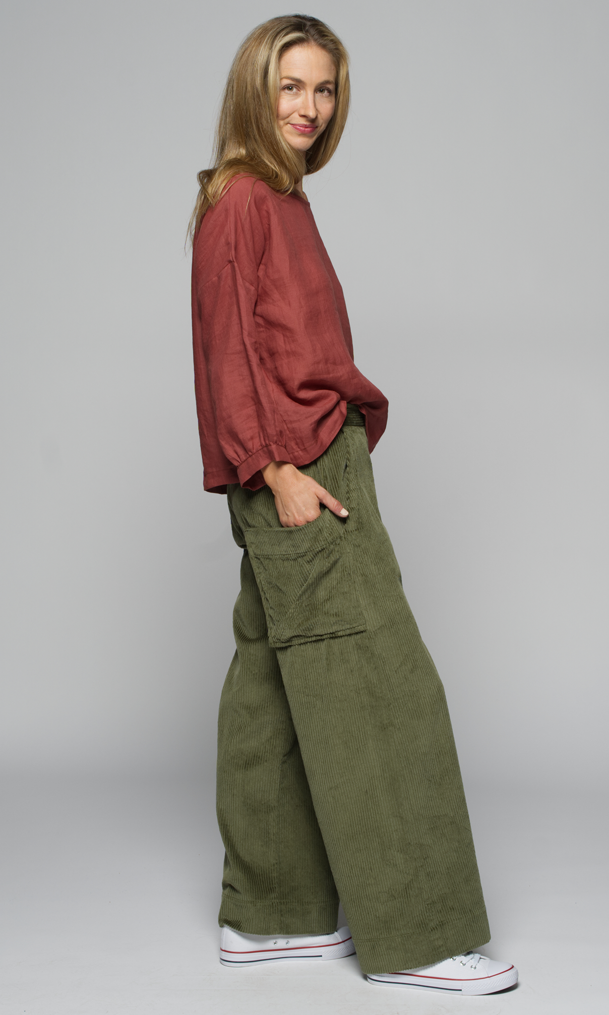 A woman wearing a red top and green cargo pants.