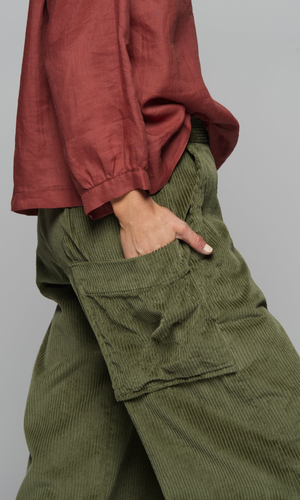 A close-up of the side pocket of a woman wearing a pair of green corduroy pants and a red long-sleeve top.