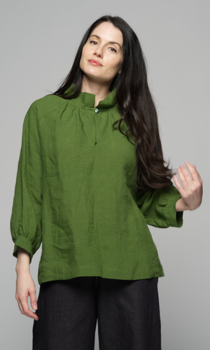 A woman wearing a long sleeve green top with black pants.
