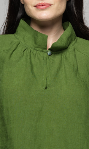 Close-up of the neckline of a woman wearing a green top.