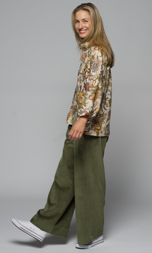 A woman wearing a floral top and green cargo pants.