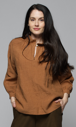 A woman wearing a long sleeve brown top with brown pants.