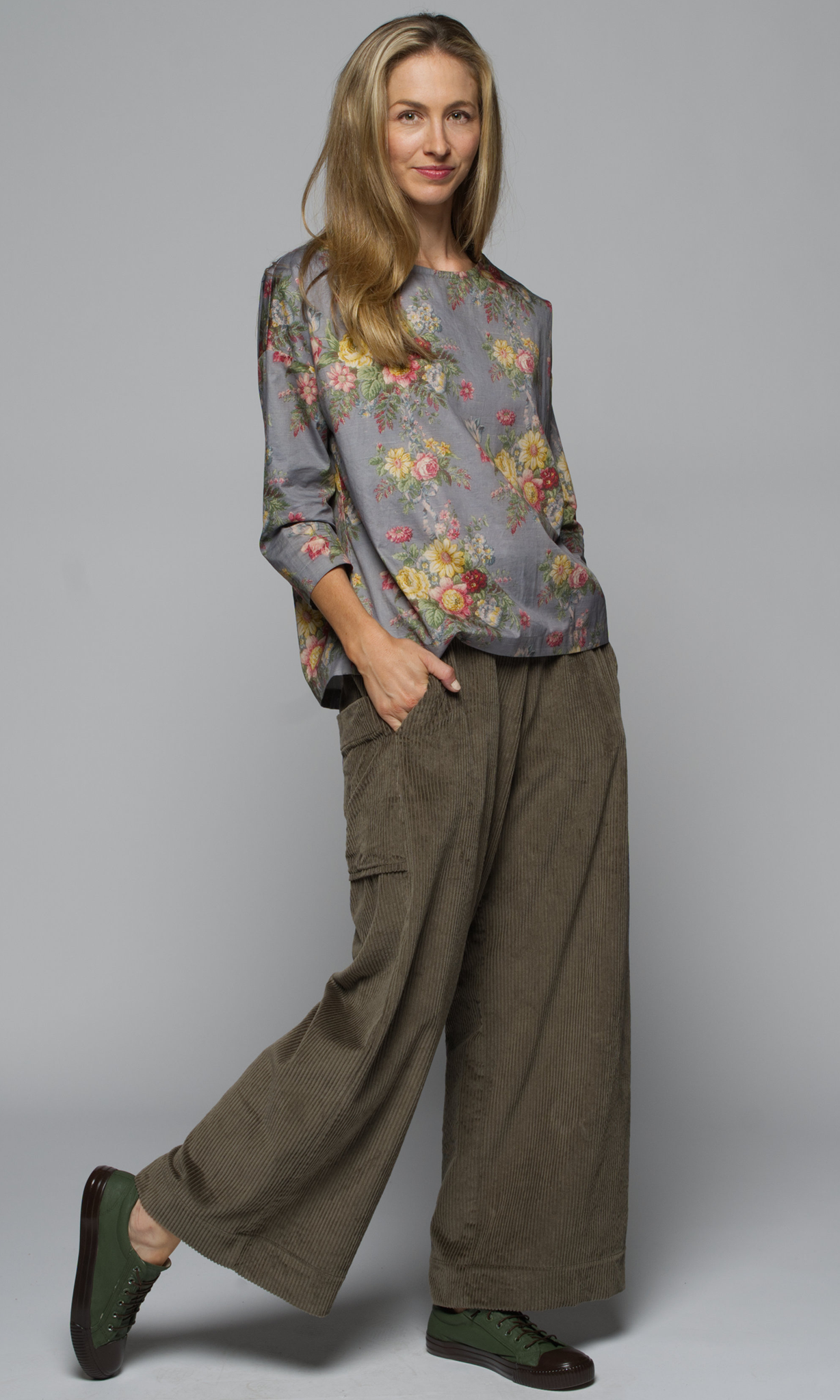 A woman wearing a floral blouse and wide-leg pants.