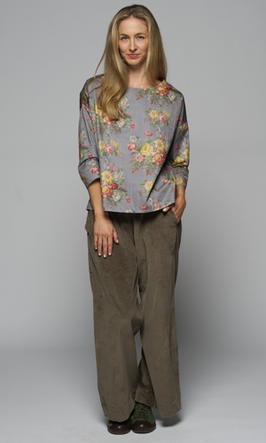 A woman wearing a floral blouse and wide-leg pants.