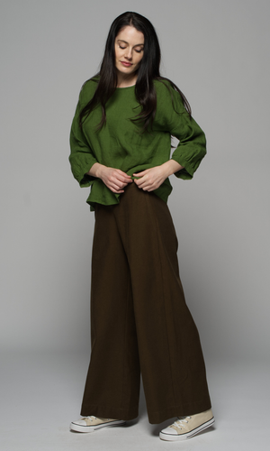 A woman wearing a green top and brown pants.