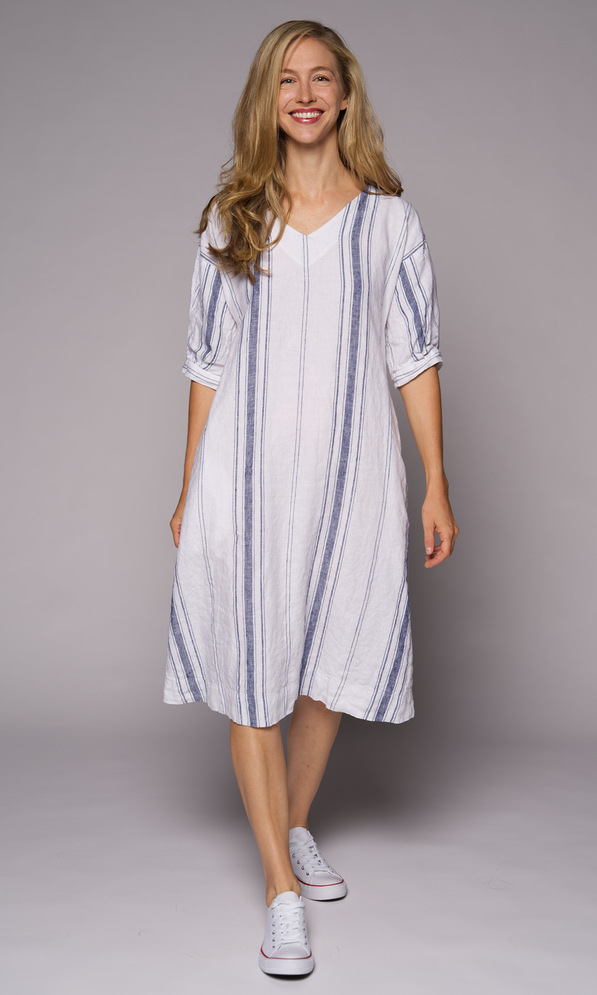 Blonde haired woman modelling a long striped linen dress.