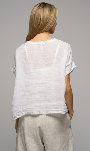 Lady in short sleeve white top with cream coloured shorts, closeup of the back of the top.
