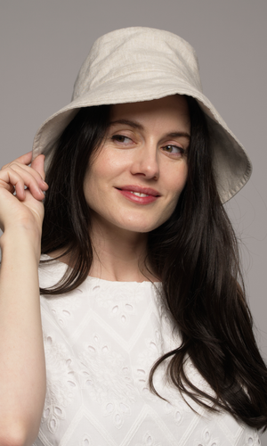 Woman with dark brown wearing a light-colored bucket hat.