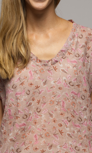 Lady wearing a short sleeve floral top showing a closeup of the slight v-neckline.