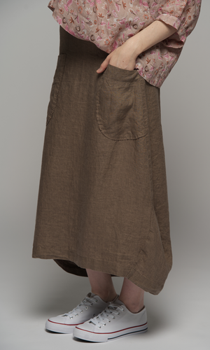 Woman wearing a elbow length floral patterned blouse with a brown skirt, close up on the skirt and pocket detail.