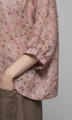 Woman wearing a elbow length floral patterned blouse with a brown skirt, showing sleeve and skirt pocket details.