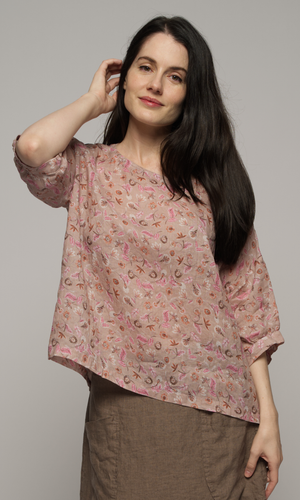 Woman wearing a elbow length floral patterned blouse with a brown skirt.